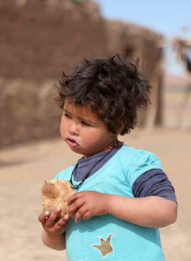 niño nómada desierto con pan en la mano